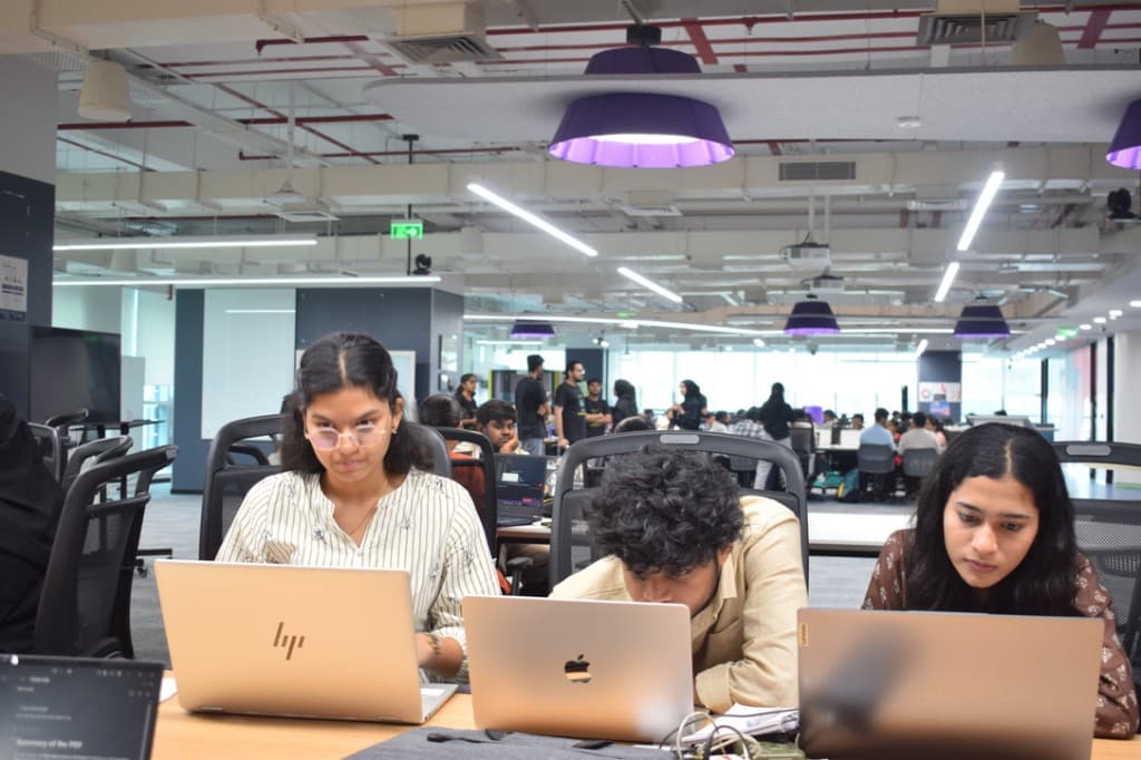 Hafsa Rumaiza, Sri Pavan Tej Balam, and Supritha building Gitora on laptops during MLH Hacktoberfest at React Hyderabad